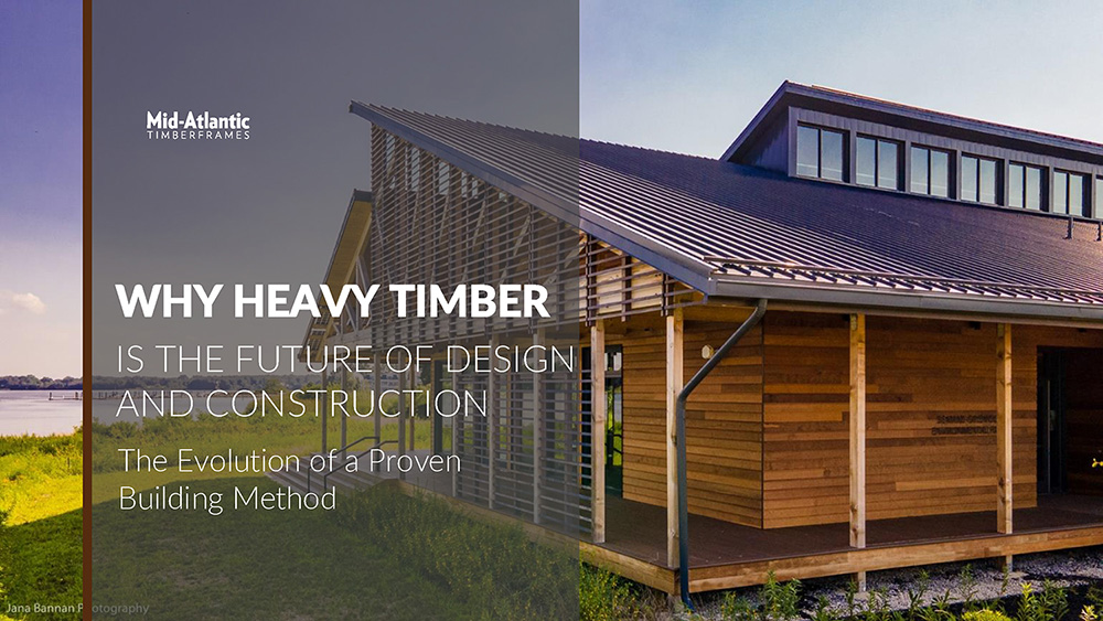 Modern wooden building with large windows under a blue sky. Overlaid text reads, “Why Heavy Timber is the Future of Design and Construction – The Evolution of a Proven Building Method” by Mid-Atlantic Timberframes.